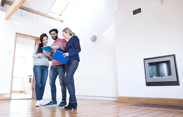 Couple observant une maison avec un agent immobilier